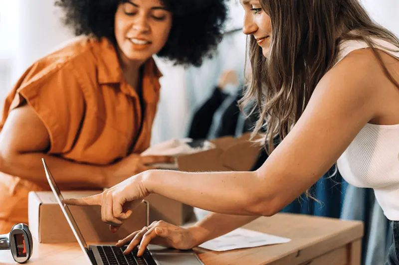 People using laptop while packaging items